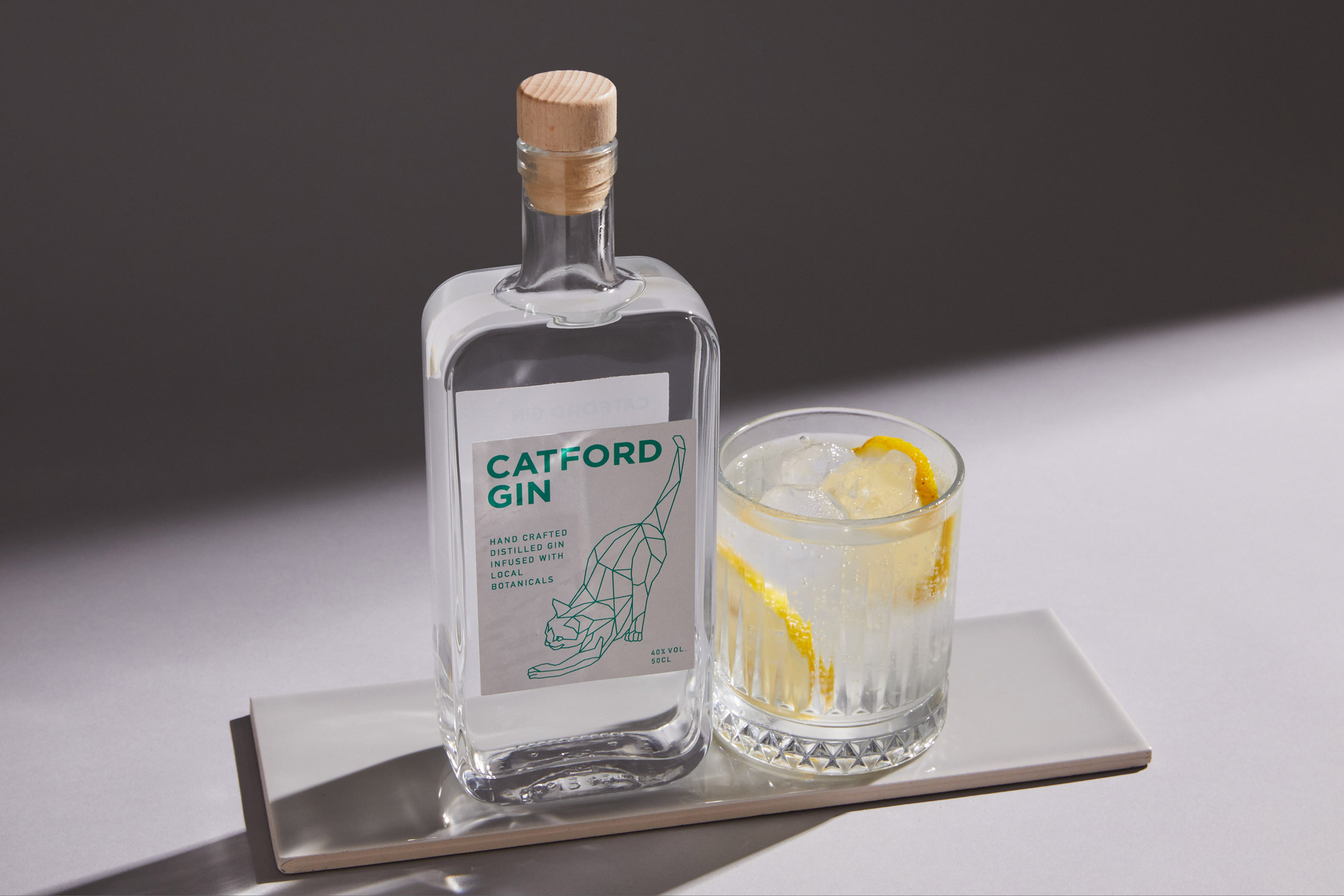 A bottle of Catford Gin with a gin and tonic garnished with lemon